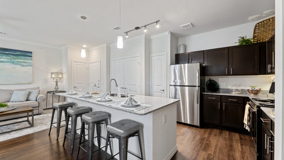 Large kitchen with espresso cabinets and kitchen island with white countertops and stainless steel appliance package in Burleson, Texas.